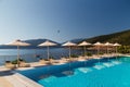 Luxury swimming pool with empty deck chairs and umbrellas at resort with beautiful sea view. Greek islands. Royalty Free Stock Photo