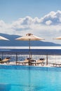 Luxury swimming pool with empty deck chairs and umbrellas at the resort with beautiful sea view Royalty Free Stock Photo