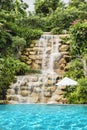 Luxury swimming pool nearby tropical forest and waterfall Royalty Free Stock Photo