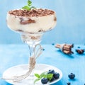 Luxury tiramisu dessert in a cocktail glass decorated with cocoa, blueberries and mint