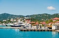 Luxury travel on boat, water transport. Yachts moored at sea pier on mountain landscape. Sea port and town on sunny blue