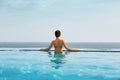 Luxury vacation travel woman relaxing in infinity swimming pool on summer beach resort. Royalty Free Stock Photo