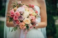 Luxury wedding bouquet of fresh flowers in the hands of bride, close-up. Delicate roses in a beautiful bouquet, blurry background Royalty Free Stock Photo