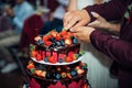 Luxury wedding cake decorated with chocolate, icing, fresh berries. Newlywed cut big beautiful cake at a wedding banquet, close-up