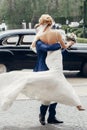 Luxury wedding couple dancing at old car in light. stylish bride and groom hugging and embracing in city street. romantic Royalty Free Stock Photo