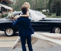 Luxury wedding couple dancing at old car in light. stylish bride and groom hugging and embracing in city street. romantic sensual Royalty Free Stock Photo