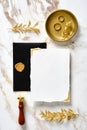 Luxury wedding stationery set. Blank invitation card mockup with black envelope, wax seal stamp, golden rings, floral leaves on Royalty Free Stock Photo