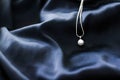 Luxury white gold pearl necklace on dark blue silk background, holiday glamour jewelery present Royalty Free Stock Photo