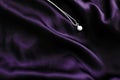 Luxury white gold pearl necklace on dark violet silk background, holiday glamour jewelery present Royalty Free Stock Photo