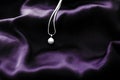 Luxury white gold pearl necklace on dark violet silk background, holiday glamour jewelery present Royalty Free Stock Photo