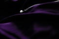 Luxury white gold pearl necklace on dark violet silk background, holiday glamour jewelery present Royalty Free Stock Photo