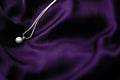 Luxury white gold pearl necklace on dark violet silk background, holiday glamour jewelery present Royalty Free Stock Photo