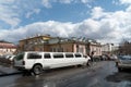 Luxury white limousine is waiting for the newlyweds in the alley on the background of the House of family celebrations after the