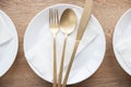 A luxury white plate, golden fork, spoon and knife with paper napkin on wooden table Royalty Free Stock Photo