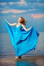 Luxury woman in a long blue evening dress on the beach. Beauty Royalty Free Stock Photo