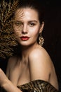 Luxury Woman Portrait with Gold Jewelry. Mystery Girl hiding Face. Glitter Make up. Elegant Lady over Black Background