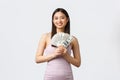 Luxury women, party and holidays concept. Beautiful smiling asian woman in evening dress, showing money, like shopping Royalty Free Stock Photo