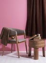 Luxury wooden chair with polished wooden table with three legs with pink wall with curtain in dark cafe in male space with books a Royalty Free Stock Photo