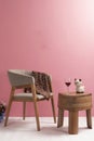 Luxury wooden chair with polished wooden table with three legs in a space with pink wall and floor in cream colors with ambient li Royalty Free Stock Photo