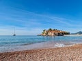 Luxury yacht floating next to idyllic island Sveti Stefan seen from sand beach, Budva Riviera, Adriatic Mediterranean Sea Royalty Free Stock Photo