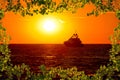 Luxury yacht on open sea at golden sunset view through leaves fr Royalty Free Stock Photo