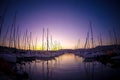 Luxury yachts docked in sea port at colorful sunset. Marine parking of motor boats. Sun and sky light reflected on the water Royalty Free Stock Photo