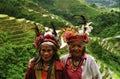 Portrait of two old indigenous women with traditional clothes and plumes headdress, blurred rice terraces background