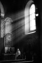 LVIV, Armenian Cathedral, UKRAINE - OCTOBER 2018:Christian woman praying. Natural sunlight shining into a medieval church.