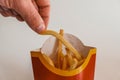 Lviv / Ukraine - April 2020: Close up view of hungry man`s hand taking a piece of french fries from Mcdonalds bag. Ordering