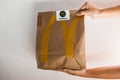 Lviv / Ukraine - April 2020: Two hands giving a paper bag with Mcdonalds takeaway food. Unhealthy eating at home during