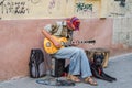 LVIV, UKRAINE - AUGUST 2016: Street musician playing rock hits of the electric guitar, sitting with a large black dog, near the wa