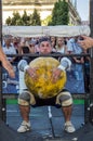 LVIV, UKRAINE - AUGUST 2017: A strong athlete a bodybuilder lifts a huge heavy stone yellow ball at Strongmen games