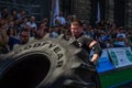 LVIV, UKRAINE - AUGUST 2017: A super strong athlete raises a huge Good year wheel at competitions in front of enthusiastic spectat