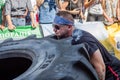 LVIV, UKRAINE - AUGUST 2017: A super strong athlete raises a huge Good year wheel at competitions in front of enthusiastic spectat