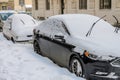 LVIV, UKRAINE - FEBRUARY 2021: In winter, on a snow-covered street there are cars covered with snow