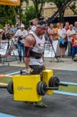 LVIV, UKRAINE - JULY 2016: Mighty strong athlete bodybuilder strongman carries heavy iron suitcases on the street in front of