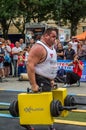LVIV, UKRAINE - JULY 2016: Mighty strong athlete bodybuilder strongman carries heavy iron suitcases on the street in front of