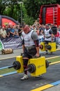 LVIV, UKRAINE - JULY 2016: Mighty strong athlete bodybuilder strongman carries heavy iron suitcases on the street in front of