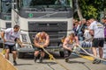 LVIV, UKRAINE - JULY 2016: Two strong athlete bodybuilder strongman pulling with ropes two huge truck in front of enthusiastic Royalty Free Stock Photo