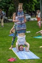 LVIV, UKRAINE - JUNE 2016: Coach instructor teaches a young charming girl with a sports figure to stand on his head during yoga Royalty Free Stock Photo