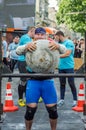 LVIV, UKRAINE - JUNE 2016: Strong bodybuilder strongman lifts a huge heavy stone ball made of marble and throws it over the bar on