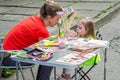 LVIV, UKRAINE - JUNE 2016: Woman master artist paints a sweet charming girl child on the face of mustache and a cat mask on a