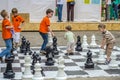 LVIV, UKRAINE - JUNE 2016: Young children, the future grandmasters play on a chess board chess exercising outdoors huge figures