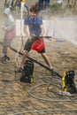 Happy boy pours water from a hose passersby. Royalty Free Stock Photo