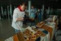 Girl in chef uniform serving snacks on table for degustation in Lviv airport hall