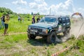 LVIV, UKRAINE - MAY 2016: Huge tuned car Jeep SUV driving on a dirt road rally, raising a cloud of dust behind, among the Royalty Free Stock Photo