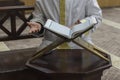 The Koran is opened on a stand in front of a mullah. Selective focus on pages