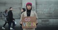 Lviv, Ukraine - November 27, 2019: Young hipster girl holding Go Vegan sign banner and standing outside. Time lapse