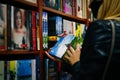 Lviv, Ukraine - 26.09.2021: reading concept. Woman selecting book from a bookshelf. Female hand picks up a book from a