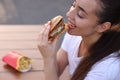 Lviv, Ukraine - September 26, 2023: Woman eating McDonald\'s burger outdoors, closeup